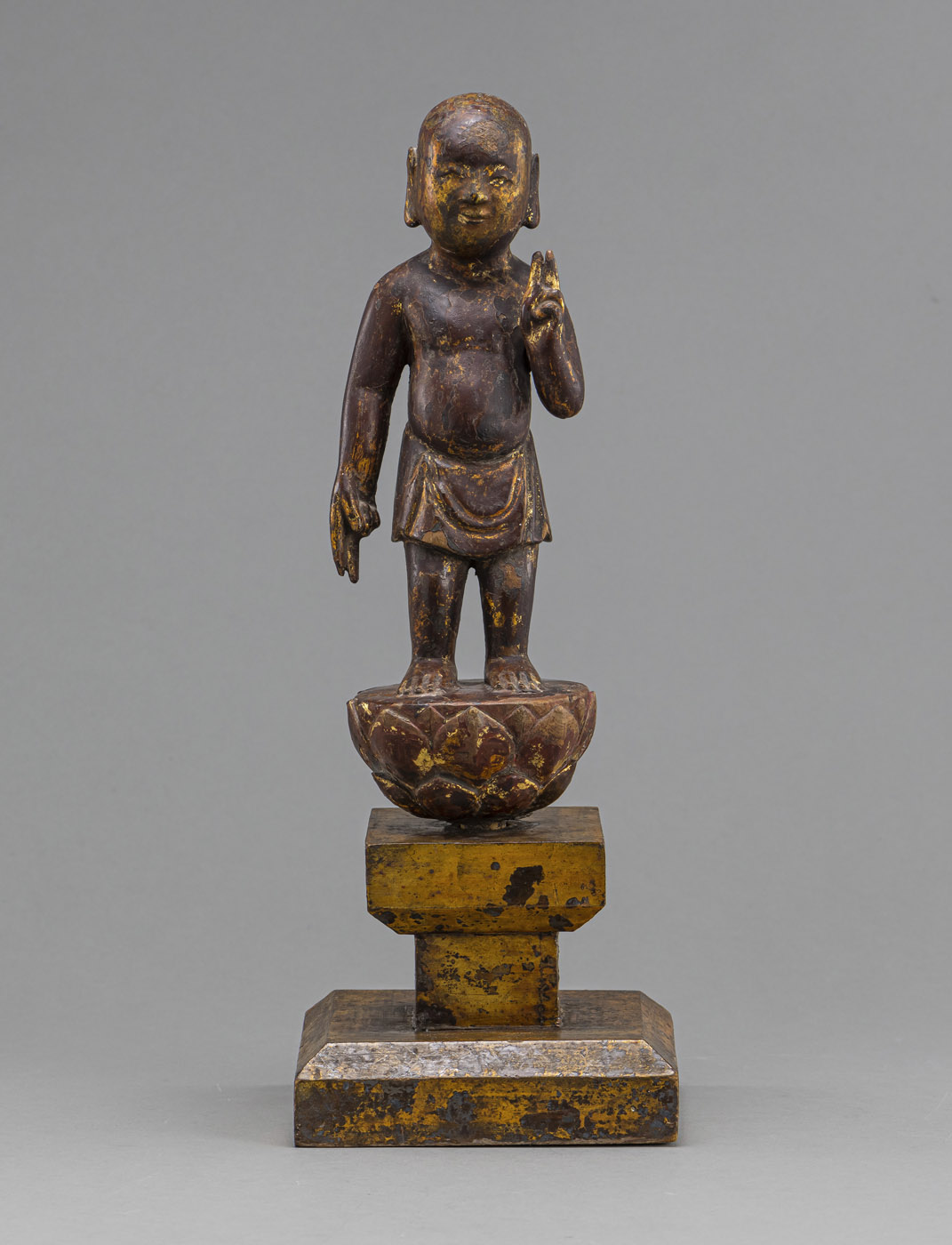 <b>BUDDHA AS A NEWBORN STANDING ON A LOTUS BASE, WOOD WITH GOLD LACQUER, MOUNTED ON A LATER HIGH PEDESTAL</b>