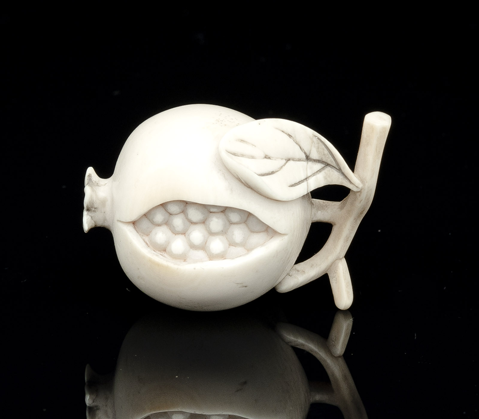 <b>AN IVORY NETSUKE OF A POMEGRANATE</b>