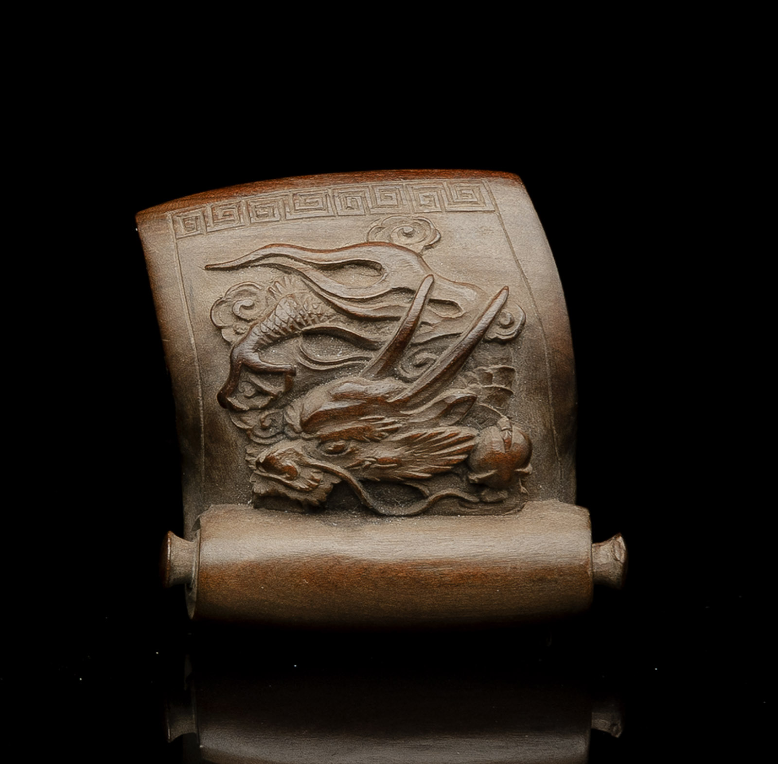 <b>Netsuke aus Holz in Form eines Rollbilds mit reliefierter Darstellung eines Drachens</b>