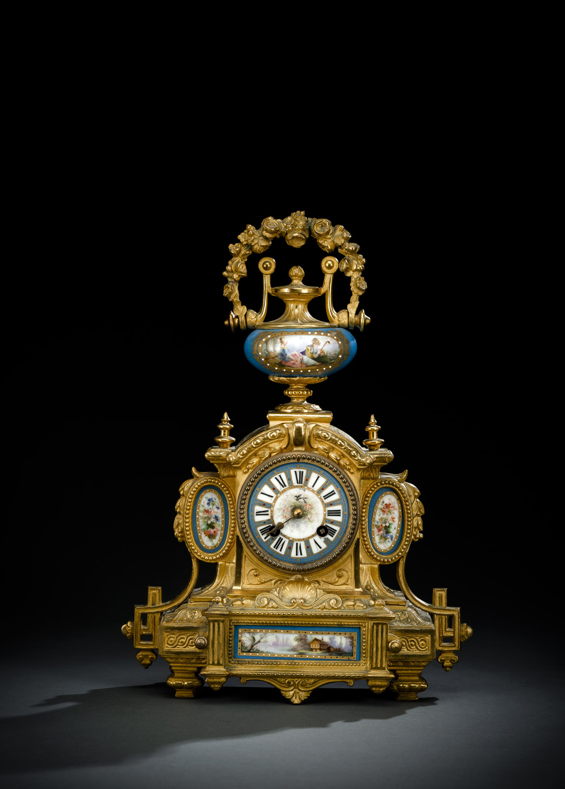 Gilded bronze case with movable handle on top and porcelain plaques in Sèvres style. Blue fond, polychrome painted and gilded porcelain. Porcelain dial with Roman numerals, one hand is missing. Parisian movement with 8 day going, half-hour striking on bell, spring suspension. Pendulum missing. Stamped on the reverse: P.H. MOUREY 77. Black lacquer underneath, rest. Running not checked.