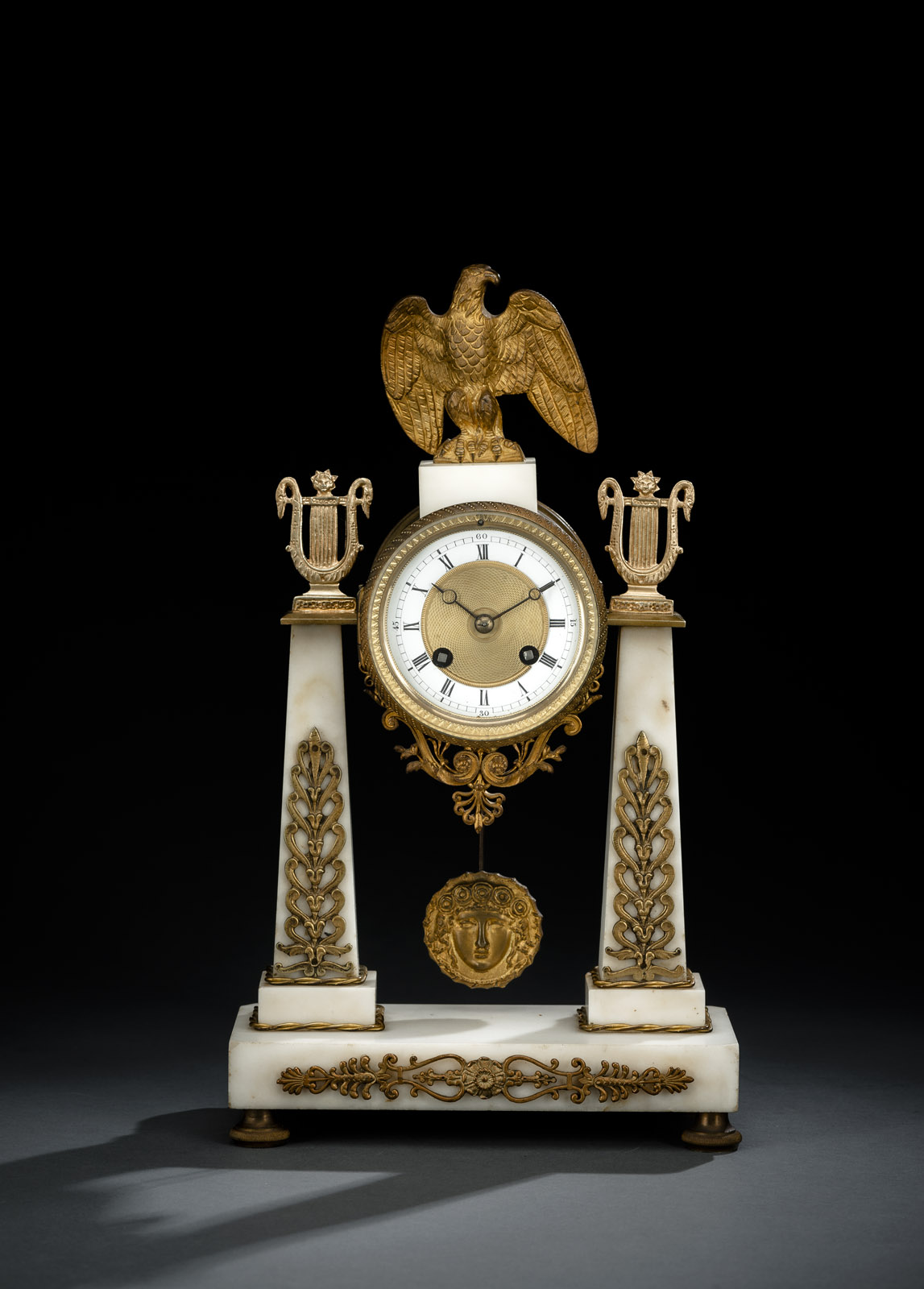 Marble with floral bronze applications, lyre and eagle coronation. Enamel dial ring with Roman numerals and minutes. Parisian work, hour striking on bell, spring suspension of Medusa pendulum. Rest., eagle and lyre later added. Running not checked.