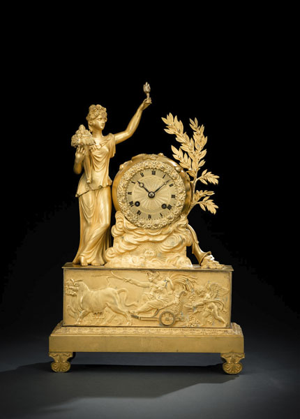 Fire-gilded bronze case with a three-dimensional representation of Demeter with a cornucopia and a sun motif in a band of clouds. Chariot with bundles of wheat in the base relief. Gilt dial with Roman numerals and blued hands. Parisian work with 8 day going, half hour striking on bell and thread suspension of the pendulum (torn). Rest., running not checked. Solder on one foot.
