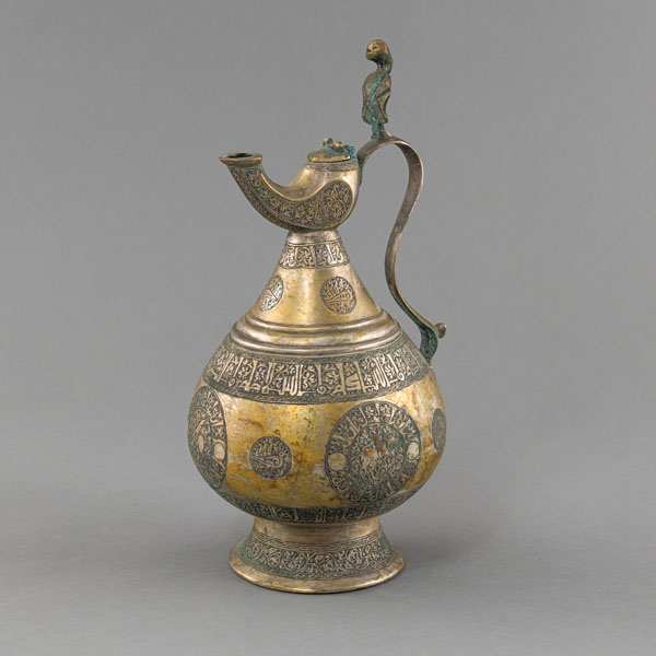 <b>AN ENGRAVED TINNED BRASS EWER WITH PSEUDO-CUFIC INSCRIPTIONS</b>