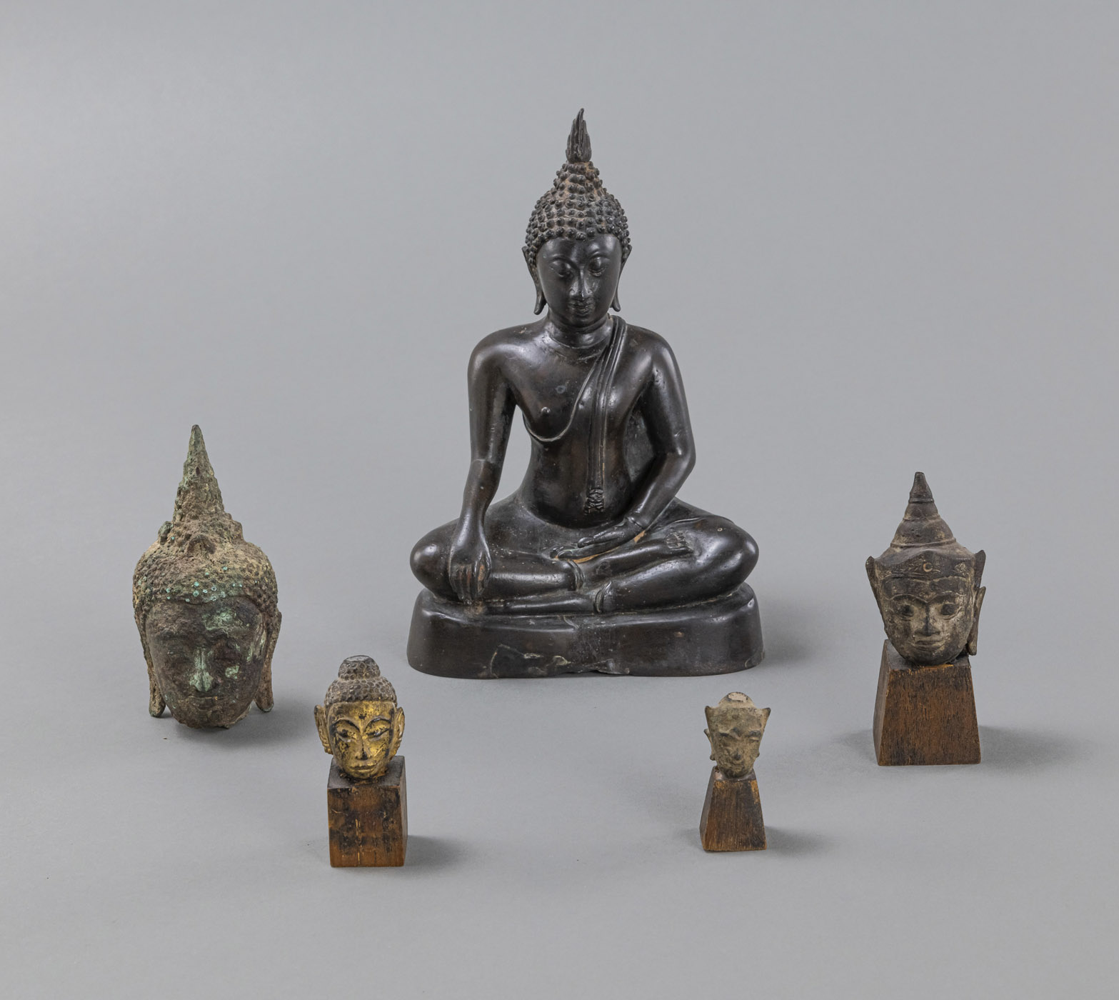 <b>A BRONZE FIGURE OF SEATED BUDDHA AND FOUR HEADS OF BUDDHA</b>