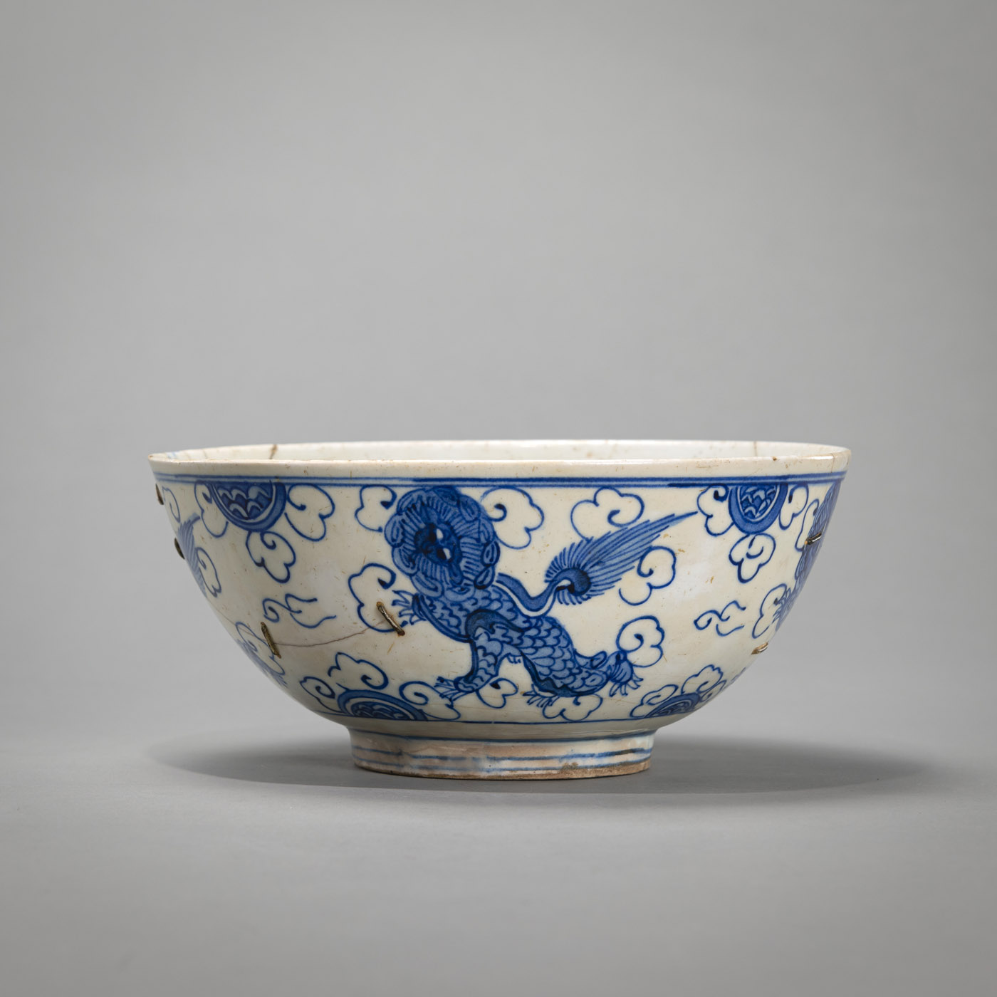 <b>A BLUE AND WHITE GLAZED POTTERY BOWL IN CHINESE STYLE WITH STYLIZED KILIN AMONG CLOUDS</b>