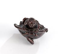 <b>A FINE WOOD NETSUKE OF AN ONI SITTING INSIDE A LOTUS LEAF</b>