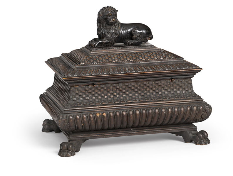 <b>Carved overal with scale and braid pattern, the rectangular moulded lid surmounted by a recumbent lion, with foliate carving and gouache painting of an amourous scene to the reverse, enclosing a fitted interior with secret drawer, on paw feet. Damages due to age, restorations.</b>