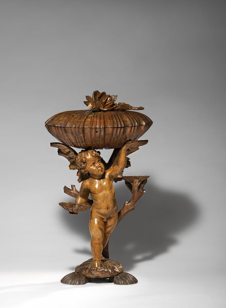 Nussbaum, der geflügelte Putto auf einer Art Schildkröte vor einem Baum mit zwei Schälchen stehend. Muschelförmige Schatulle mit Klappdeckel. Rest., Altersschäden.