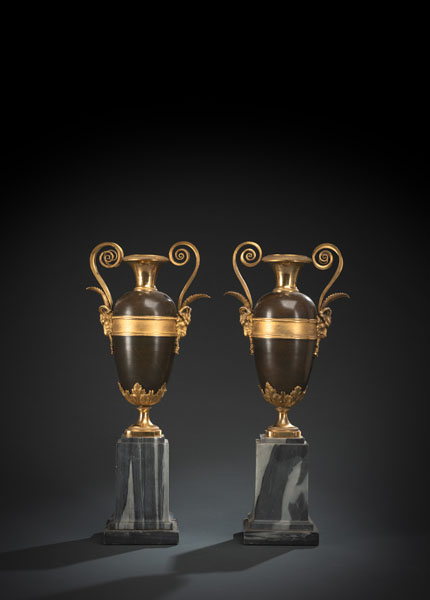 On stepped gray and white marble bases ovoid, patinated bronze vases on gilt feet with acanthus leaves, two scrolled handles above ram's heads. Marble with minor chipping, minor restoration to bronze.