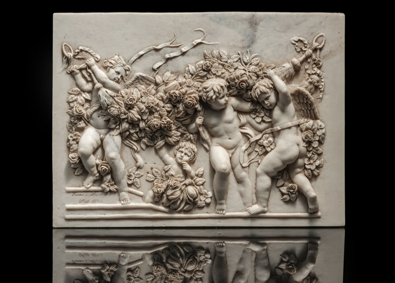 A marble relief with four putti and floral garlands. Inscribed lower left 