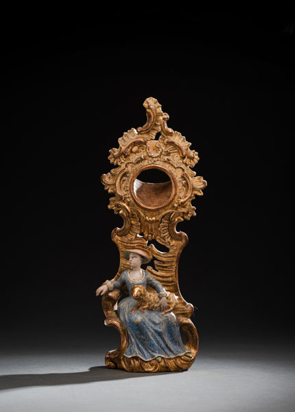 Carved hardwood, gilt and with polychromy. A lady in a blue dress sitting in front of a rocaille tower. Polychromy overpainted and worn, minor restorations.