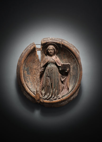 Swill pine relief carving of the Saint with book. Carved as one piece with the moulded tondo. Strong damages due to age, losses, restorations. Remnants of old polyhcromy.