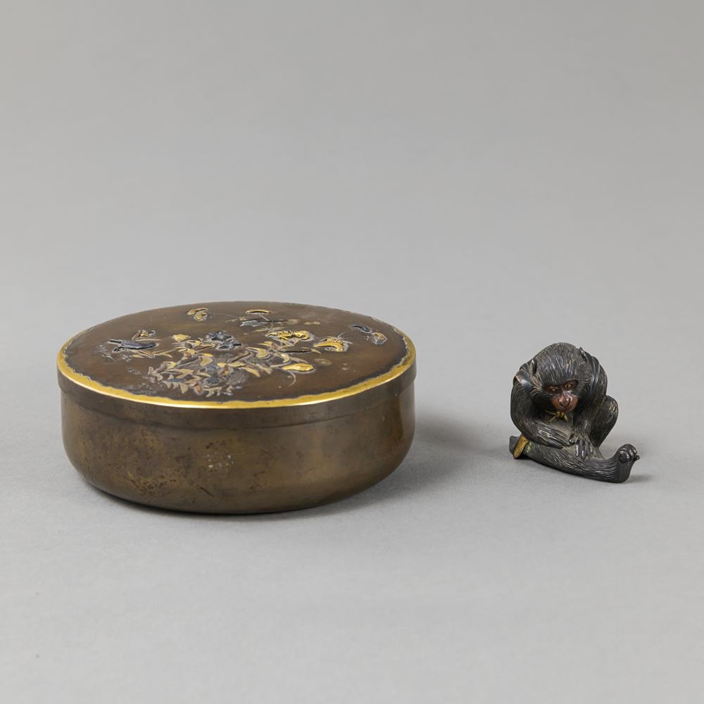 <b>A ROUND BRONZE LIDDED BOX WITH FLORAL AND BIRD DECORATION AND A BRONZE MONKEY OKIMONO; GOLD AND SILVER INLAYS</b>