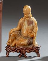 <b>A CARVED AND ENGRAVED SOAPSTONE FIGURE OF SEATED SHOULAO ON A CARVED WOOD STAND</b>