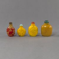 <b>FOUR SNUFF BOTTLES MADE OF YELLOW OR AMBER-COLORED GLASS, PARTLY CARVED IN RELIEF DECORATION WITH GOLDFISH IN RED OVERLAY A.O.</b>