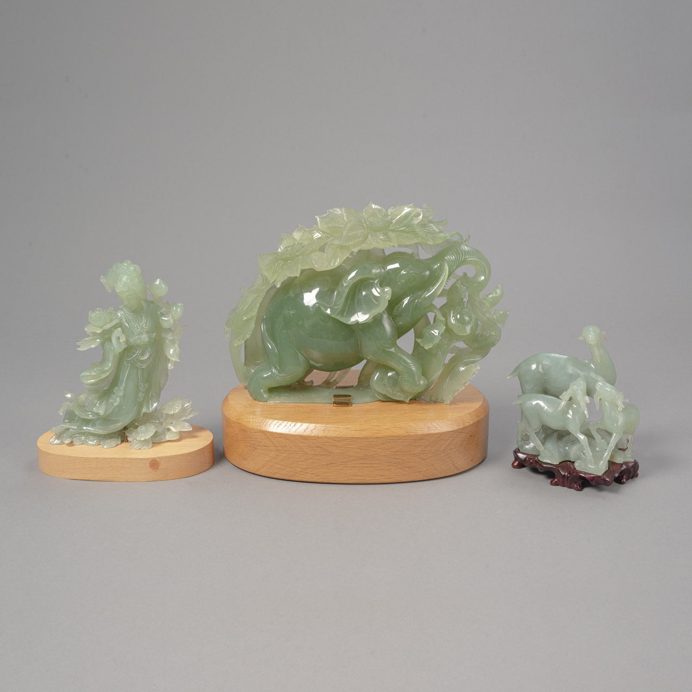 <b>Drei Schnitzereien aus Xiu-Jade (Serpentin): Elefant, drei Widder und Xi Wang Mu mit Pfirsichen, jeweils auf Sockel</b>