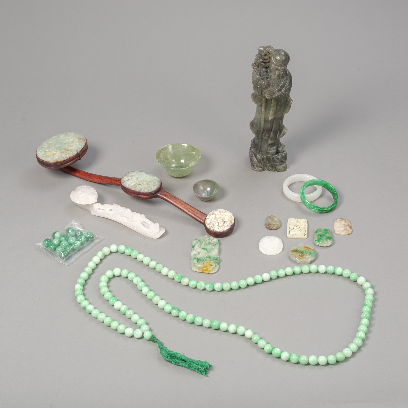 <b>Konvolut Jade- und Stein-Arbeiten: zwei Zepter, ein stehender Shoulao, zwei Schalen, eine Kette, zwei Armreifen, sieben Anhänger und lose Perlen</b>