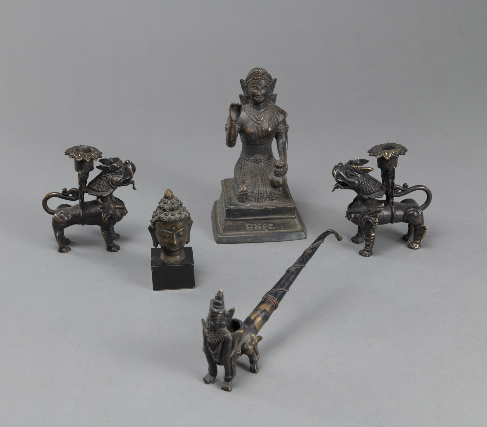 <b>Konvolut Bronzeskulpturen: Kopf des Buddha, Adorant, Pfeife und Paar Kerzenhalter</b>