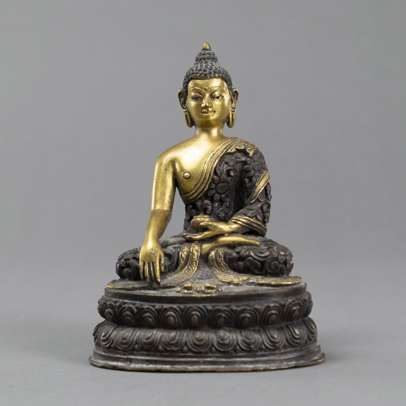 <b>Sitzender Buddha Akshobhya aus Bronze teils vergoldet, mit Almosenschale und in reliefiertem Gewand</b>