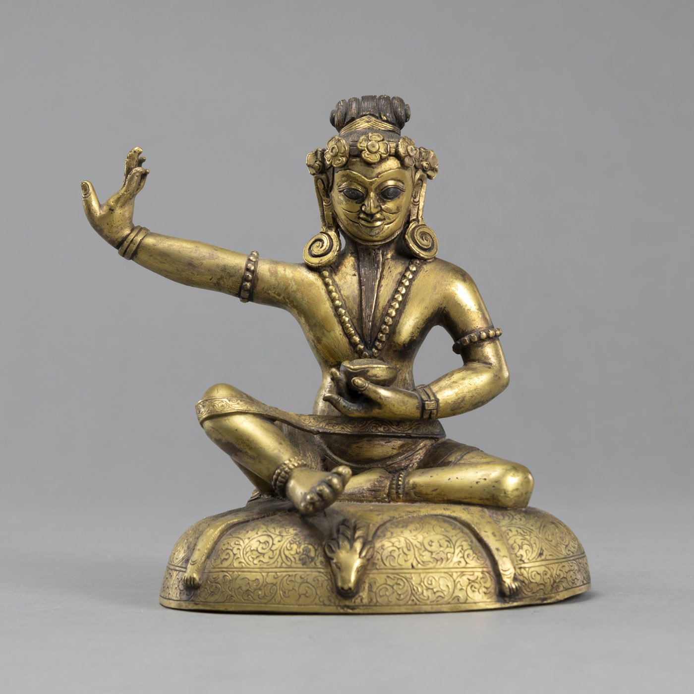 <b>A SEATED GILT BRONZE MAHASIDDHA ON A CUSHION</b>