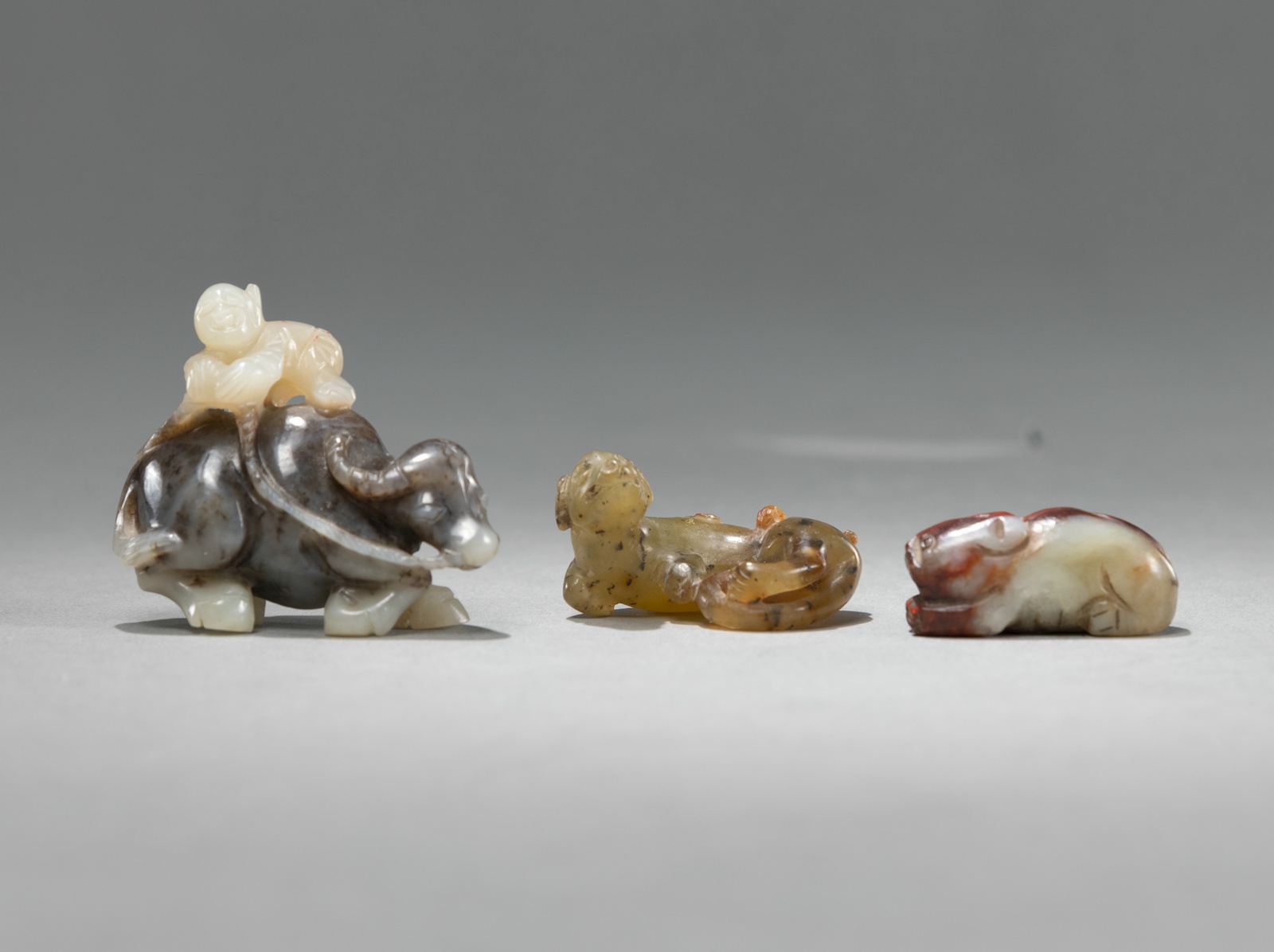 <b>Drei kleine Jade- und Steinschnitzereien: Knabe auf Büffel, Hund und Katze</b>