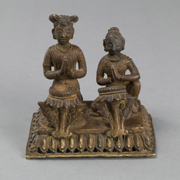 <b>A GILT-COPPER OILLAMP WITH A KNEELING WORSHIPPING COUPLE ON A RECTANGULAR LOTUS BASE</b>