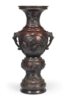 <b>A LARGE BRONZE VASE WITH TWO BAKU HEAD HANDLES AND RESERVES DEPICTING FLOWERS AND BIRD IN RELIEF ON A HIGH BASE</b>