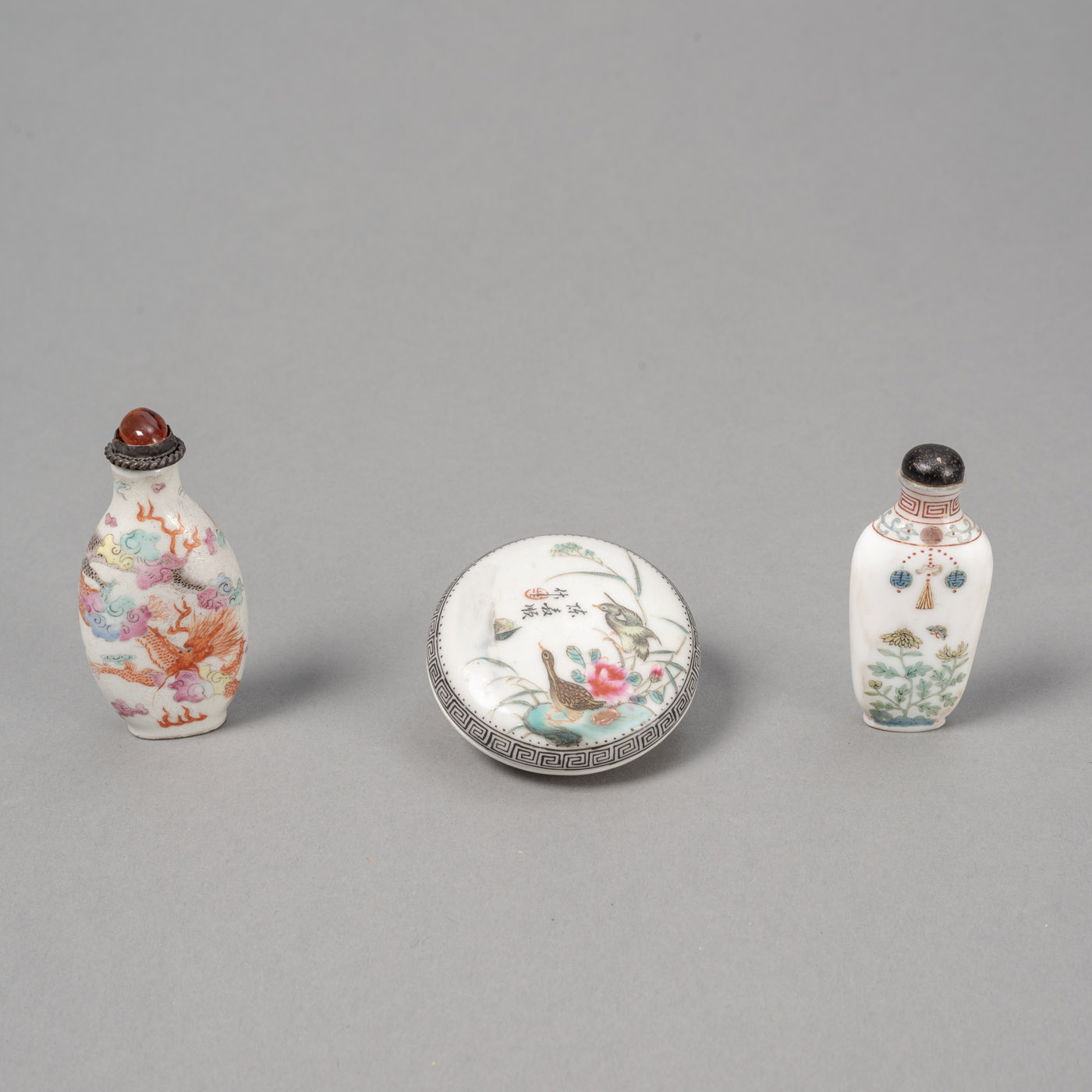<b>Zwei fein polychrom bemalte Porzellan-Snuffbottles mit Drachen- und 'Gu Yue Xuan'-Dekor sowie eine Siegellackdose mit Entenpärchen am Ufer in zarter Emailmalerei</b>