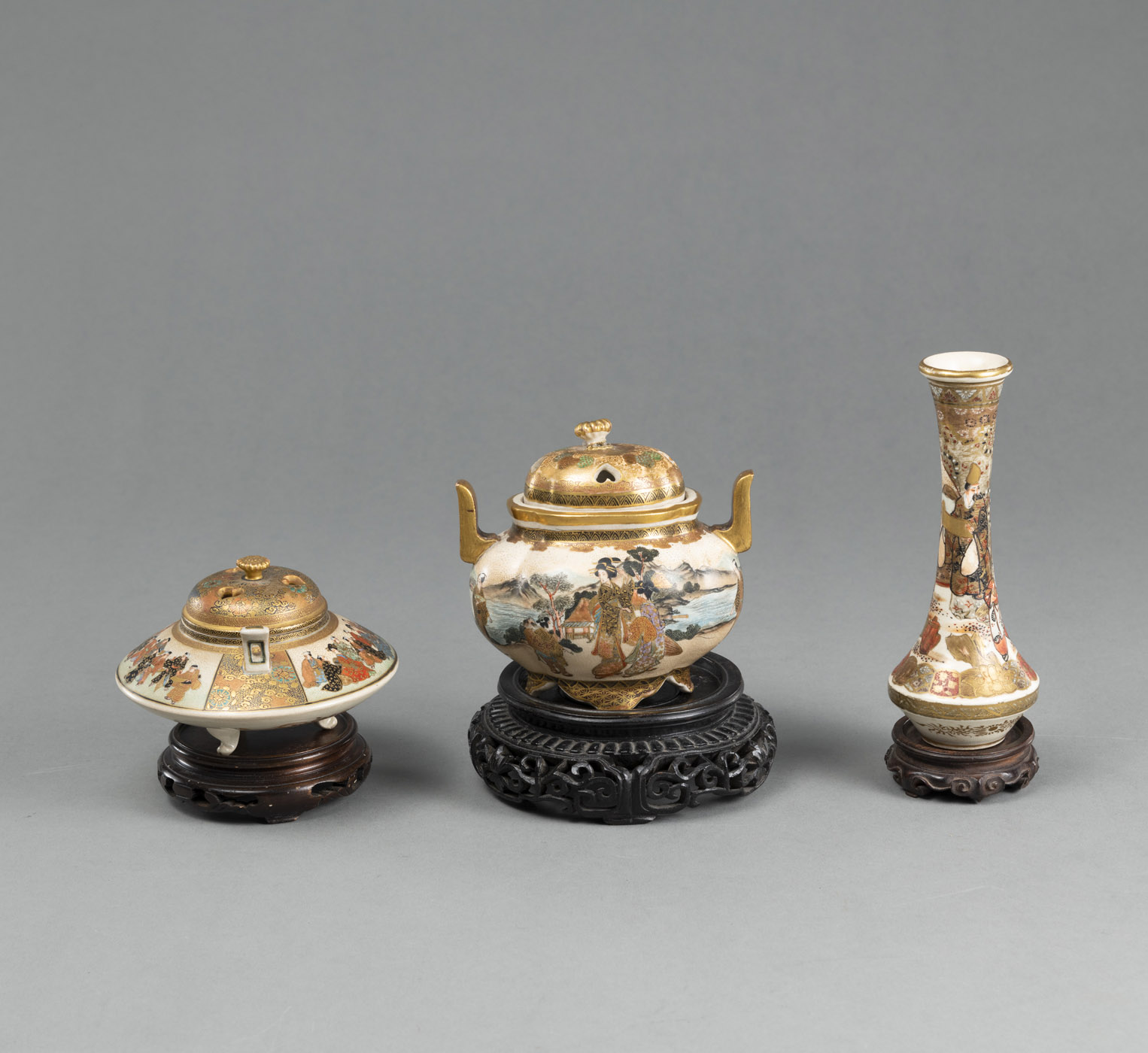 <b>TWO SATSUMA STONEWARE KORO (INCENSE BURNER) WITH OPENWORK COVERS AND A SMALL VASE, ALL WITH FIGURAL DECORATION, EACH WITH A WOODEN BASE</b>