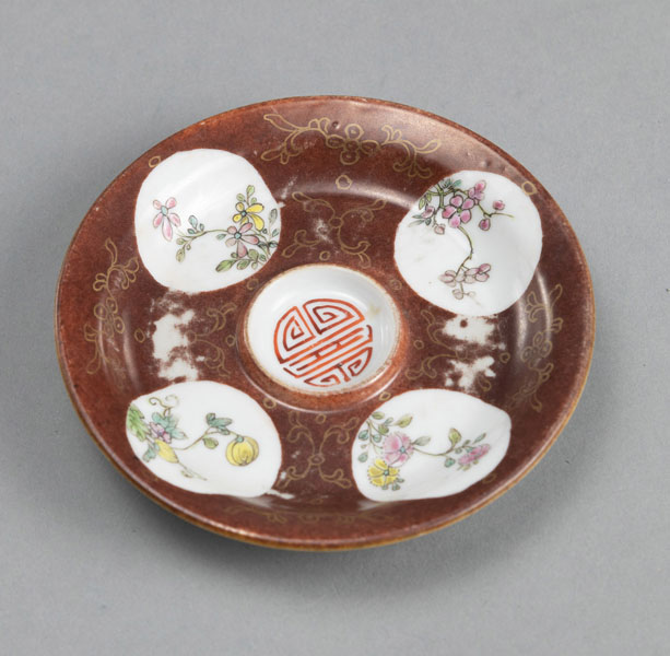 <b>A SMALL REDDISH-BROWN GLAZED SAUCER WITH A 'SHOU' CHARACTER AND FOUR FLORAL MEDALLIONS IN POLYCHROME ENAMELS</b>