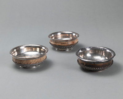 <b>THREE ROOT WOODEN TEA BOWLS (PHORBA), PARTLY MOUNTED WITH SILVER, DECORATED WITH DRAGONS AND BUDDHIST SYMBOLS</b>