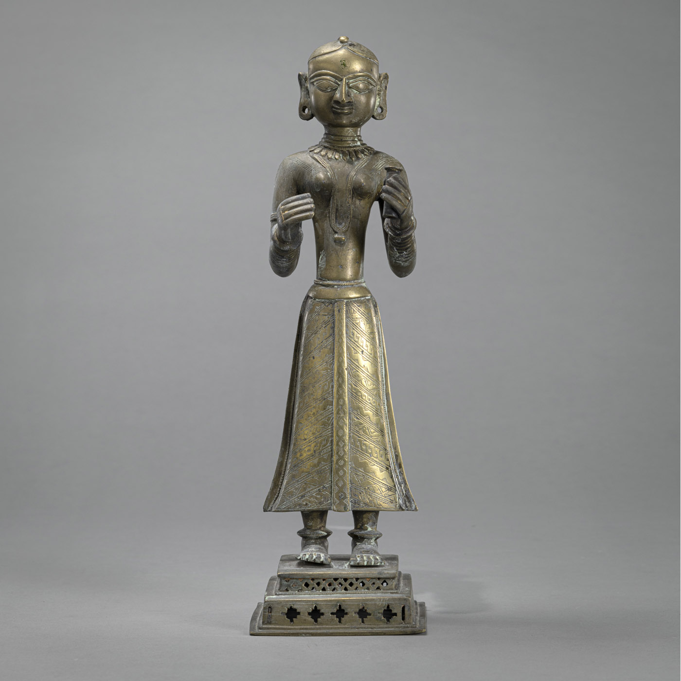 <b>A STANDING BRONZE ADORANT MOUNTED ON A STEPPED PEDESTAL</b>