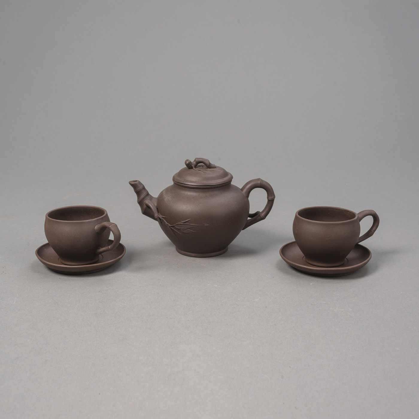 <b>A YIXING DARK BROWN ZISHA CLAY TEAPOT WITH BAMBOO DECORATION AND TWO CUPS AND TWO SAUCERS IN A BOX</b>