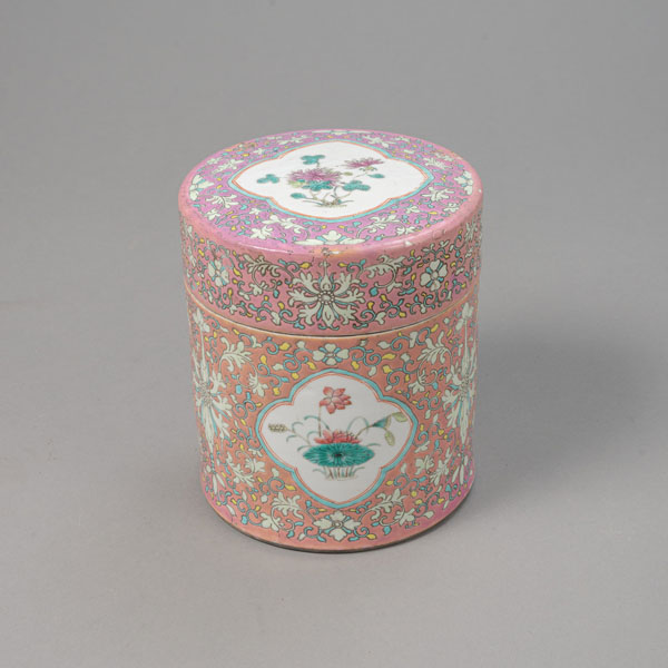 <b>A CYLINDRICAL 'FAMILLE ROSE' PORCELAIN POT AND COVER DEPICTING FLOWERS OF THE FOUR SEASONS IN CARTOUCHES ON A LOTUS BACKGROUND</b>