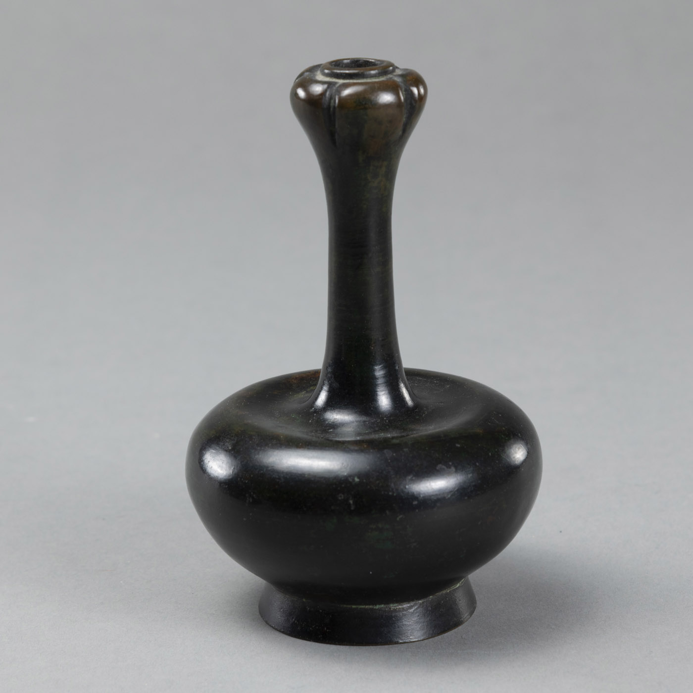 <b>A SMALL LONG-NECKED BRONZE VASE WITH A GARLIC-SHAPED MOUTH</b>