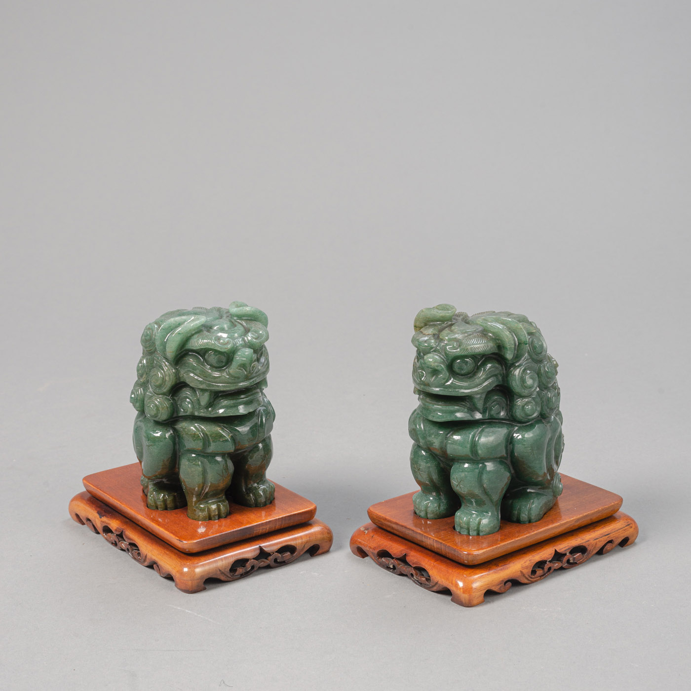 <b>A PAIR OF BAVENITE BUDDHIST LIONS ON CARVED WOOD STANDS</b>