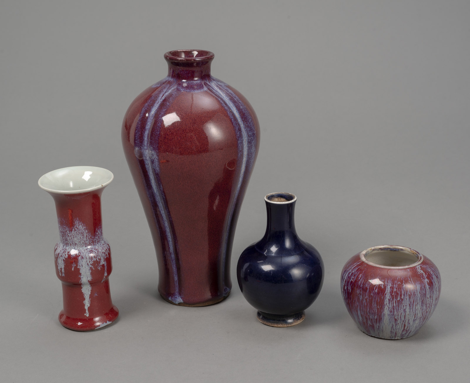 <b>TWO FLAMBÉ-GLAZED VASES AND A BRUSH WASHER, WITH ANOTHER BLUE-GLAZED BOTTLE VASE</b>