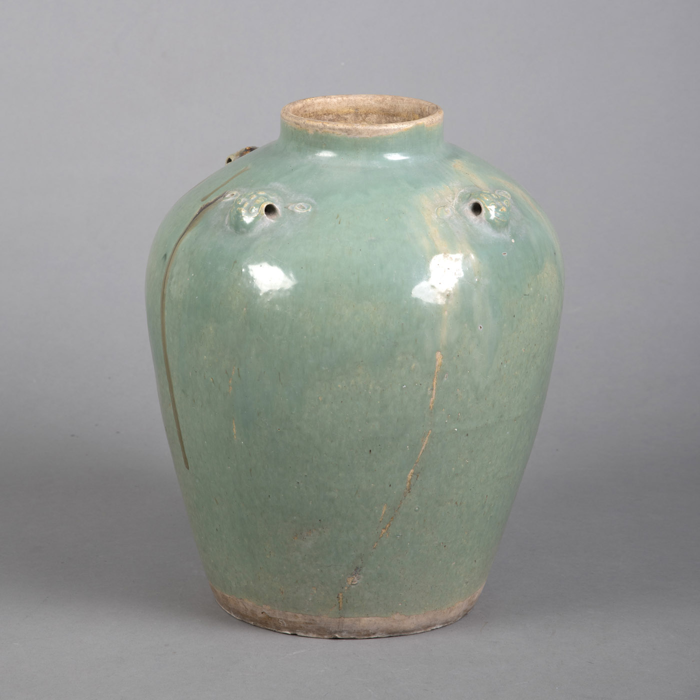 <b>A MINT GREEN AND BROWN GLAZED CERAMIC SHOULD POT WITH FOUR MASK EYELETS</b>
