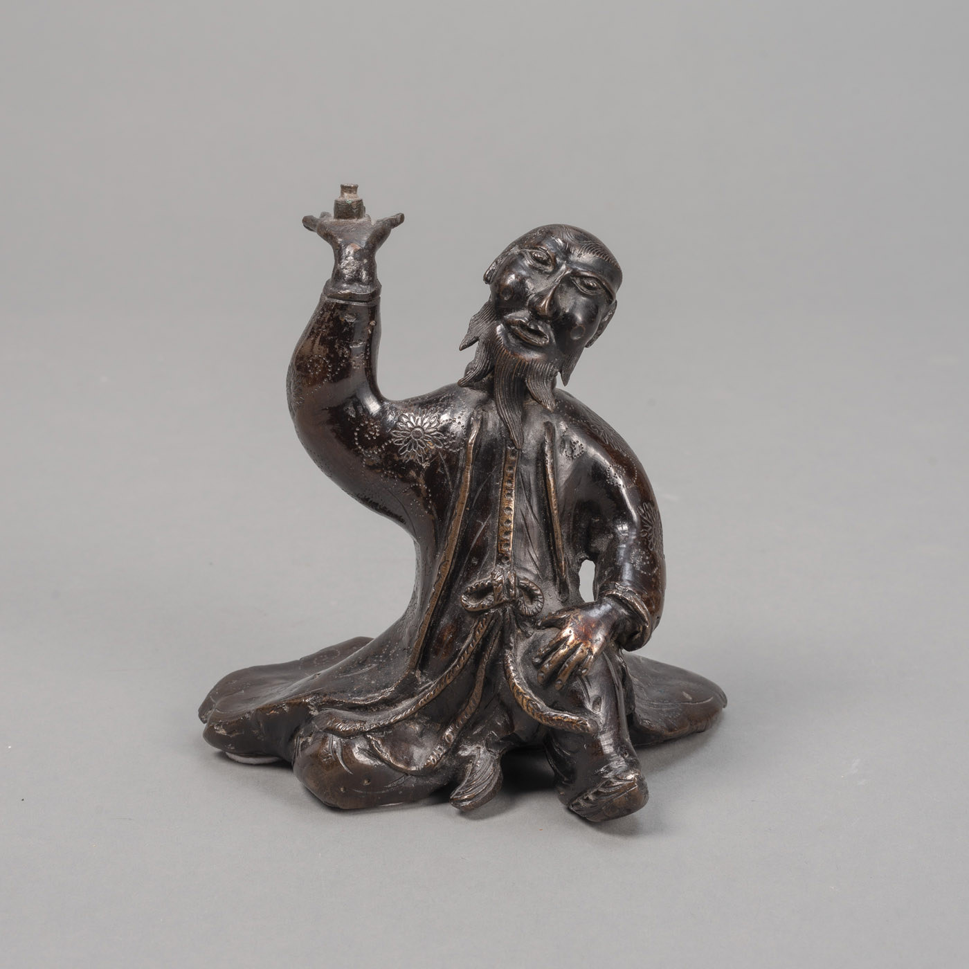 <b>A BRONZE OKIMONO OF A SEATED EUROPEAN AS A CANDLESTICK</b>