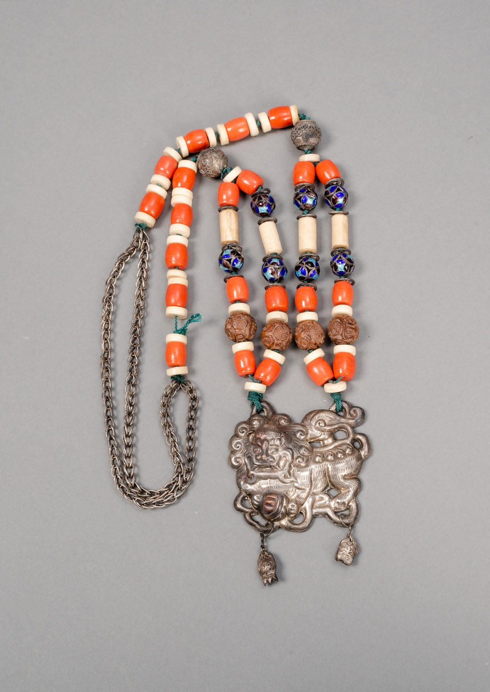 <b>Kette mit Anhänger in Form eines buddhistischen Löwen aus Silber, Holz, Email und roter Koralle</b>
