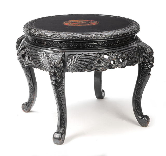 <b>Vierbeiniger runder Tisch aus Holz mit Reliefdekor und zentralem, polychromem Drachen-Medaillon auf der Platte</b>