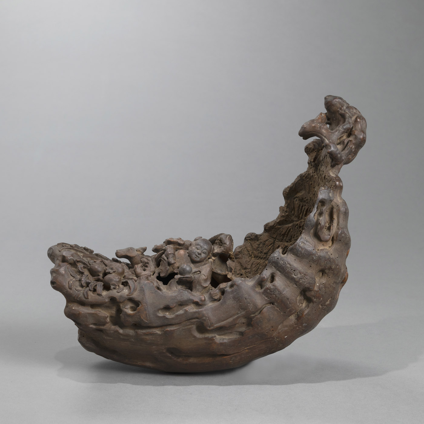 <b>A BAMBOO CARVING IN THE SHAPE OF A BOAT LOADED WITH AUSPICIOUS SYMBOLS: A BOY WITH LINGZHI, 'SANDUO' FRUITS, DEER AND CRANE</b>