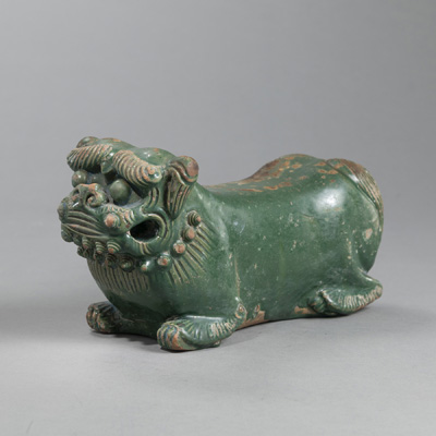 <b>A GREEN GLAZED STONEWARE NECKREST IN THE SHAPE OF A RECLINING LION</b>