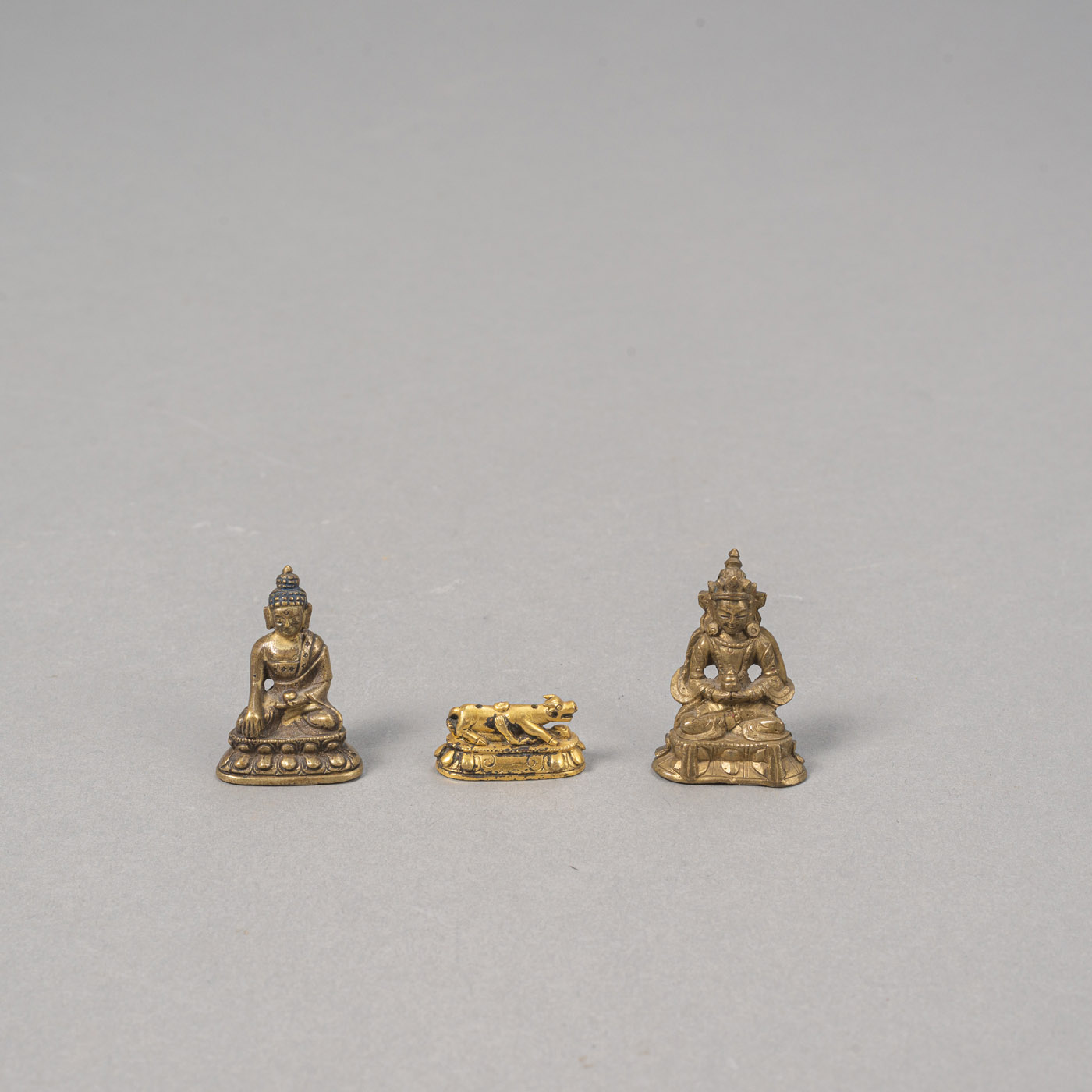 <b>Zwei Miniaturbronzen des Buddha und Amitayus und ein feuervergoldeter Miniatursockel mit Rind</b>