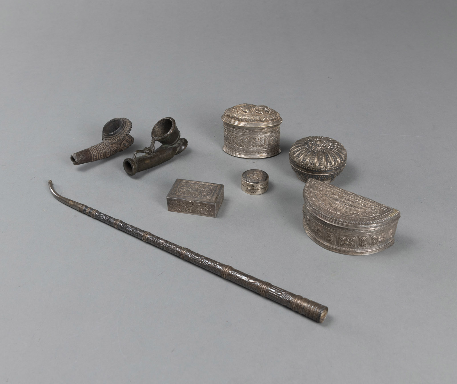 <b>A GROUP OF SILVER BETEL NUT BOXES, PIPE HEADS, AND A PIPE</b>