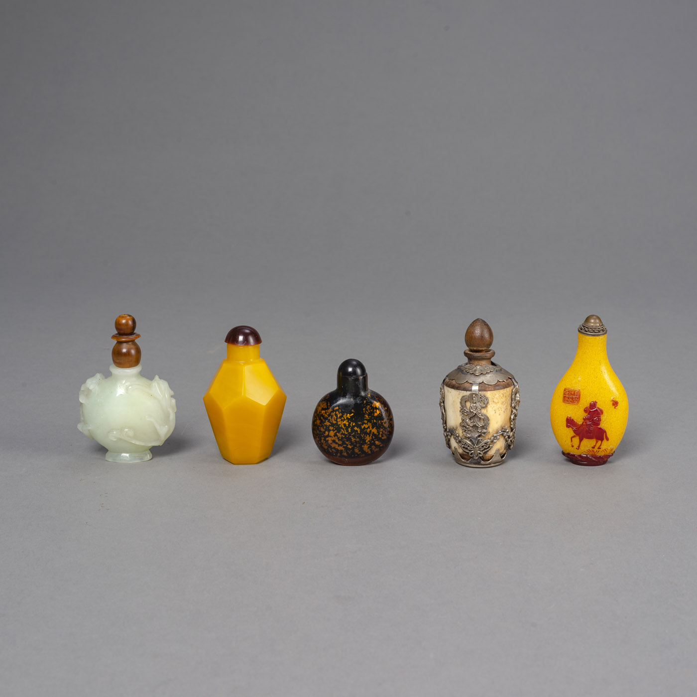 <b>Fünf Snuffbottles aus Pekingglas, Jade u. a.</b>