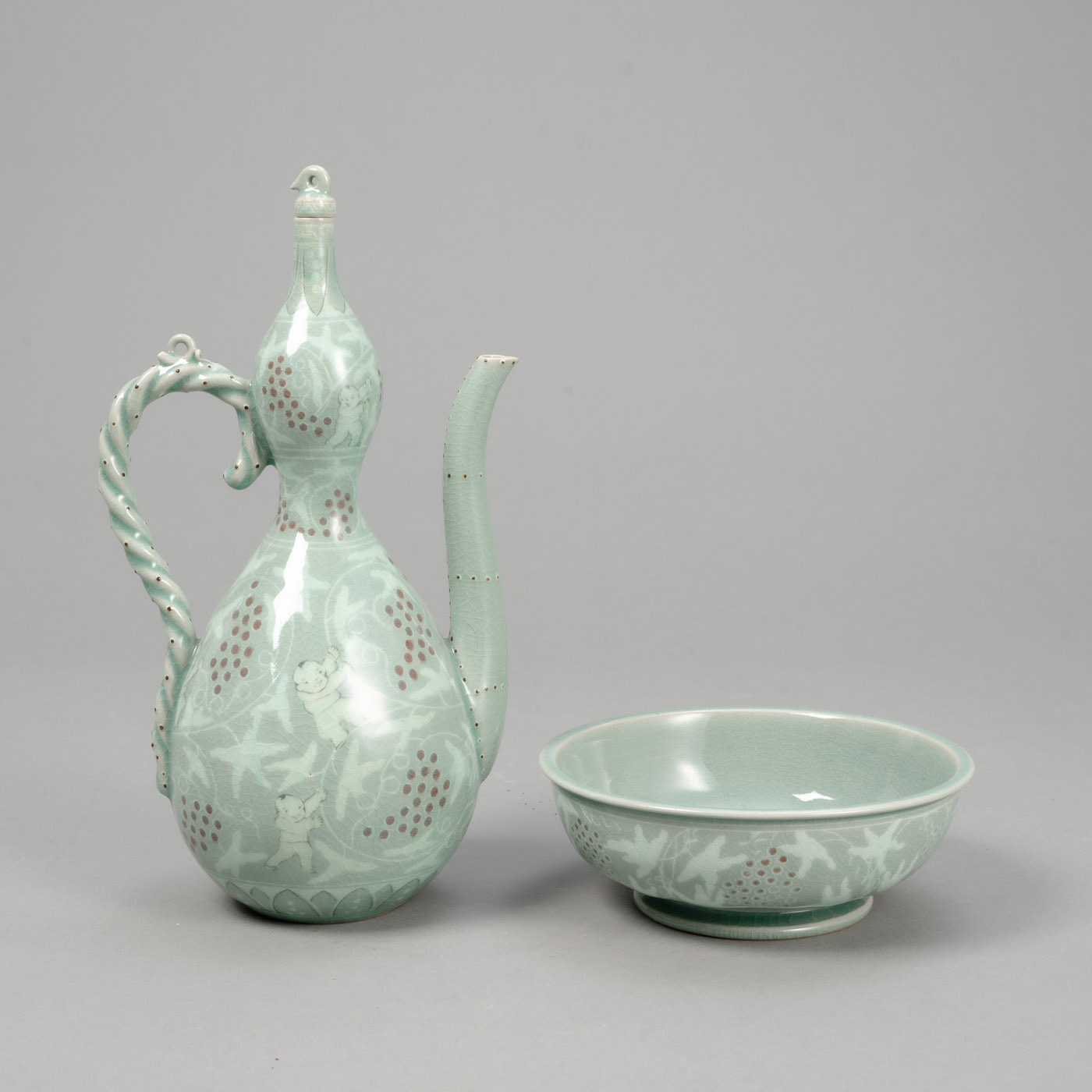 <b>YU GEUN-HYEONG (1894-1993) - AN INLAID CELADON 'BOYS' EWER WITH BASIN</b>