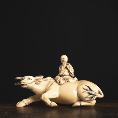 <b>AN IVORY CARVING OF A SHEPHERD BOY SEATED ON THE BACK OF AN OX</b>