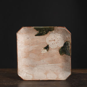 <b>Keramikplatte auf drei kurzen Standfüßen mit Dekor einer Kirschblüte mit Blättern auf rötlich beigem Grund partiell mit weißen Einschlüssen</b>
