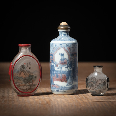 <b>Zylindrische Snuffbottle aus Porzellan mit Theaterszene 'Famen Tempel' in Unterglasurblau und Kupferrot und zwei flache Snuffbottles aus Glas mit Innenmalerei und Überfang</b>